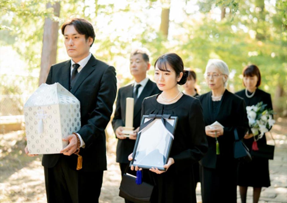 遺族が骨壷を抱えている様子