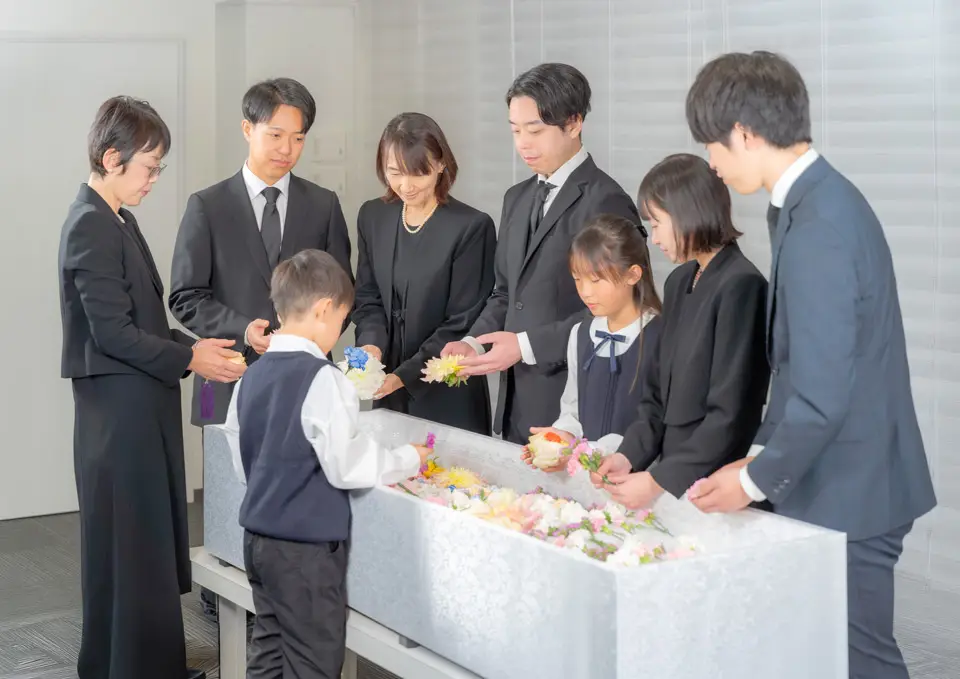 男性4名、女性4名が花束いっぱいの棺の周りに集まり、お別れ花を棺に入れている文京区での直葬(火葬式)の様子