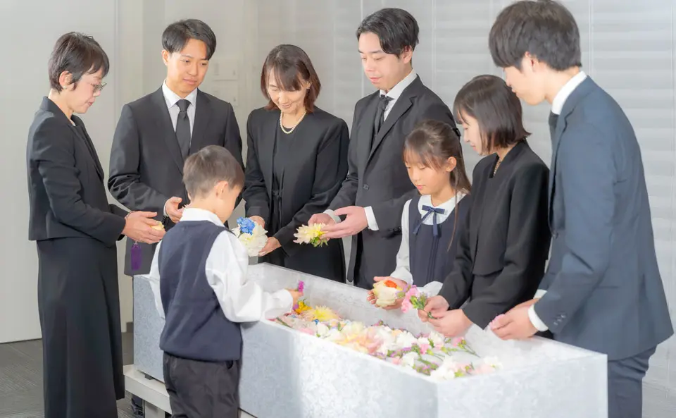 男性4名、女性4名が花束いっぱいの棺の周りに集まり、お別れ花を棺に入れている文京区での直葬(火葬式)の様子